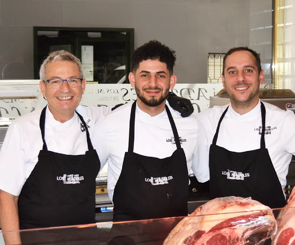 El equipo de Los Madriles con chaquetilla y delantal negro detrás del mostrador