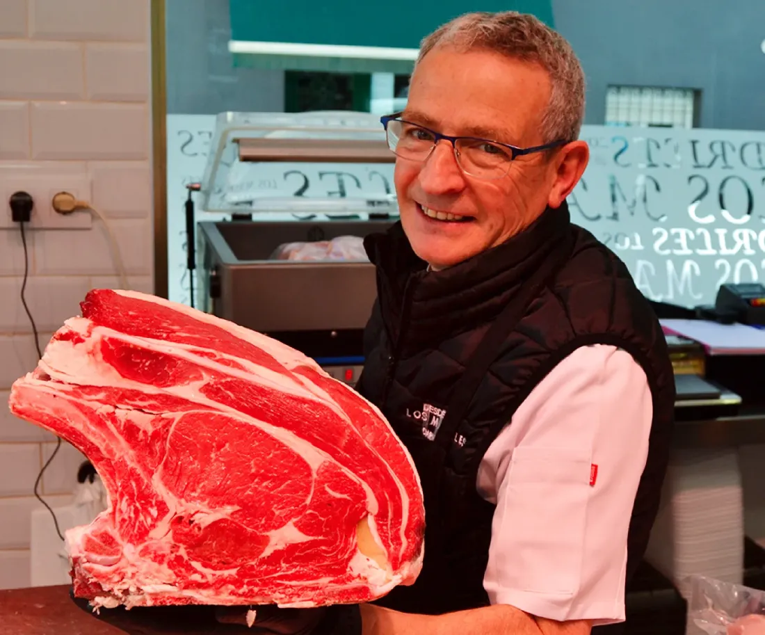 José María Madrid sonríe sosteniendo un lomo de vaca con hueso en la tienda